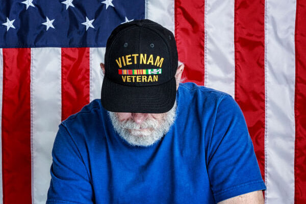 A Vietnam veteran bows his head in front of the United States flag.