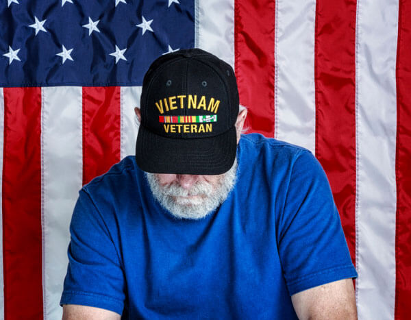 A Vietnam veteran bows his head in front of the United States flag.