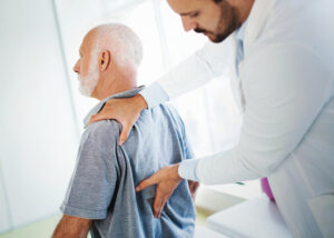  A doctor presses on a patient's lower back to check for pain.