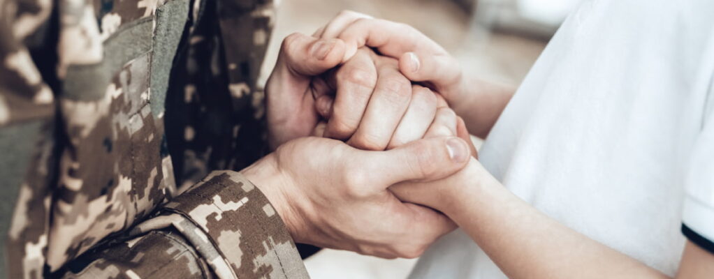 Veteran holding hands with child