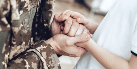 Veteran holding hands with child